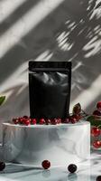Black matte bag with red berries on a marble podium against a white background photo