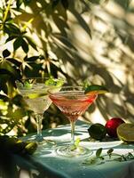 Two cocktails on a table garnished with lime and mint with a plant in the background photo