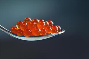 A spoonful of red caviar close up on a dark blue background photo