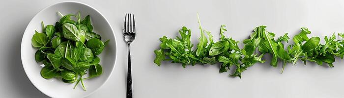 A white plate with a fork and a handful of salad greens. photo