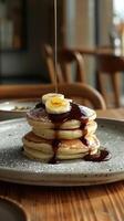 A decadent stack of pancakes smothered in chocolate sauce and topped with sliced bananas. photo