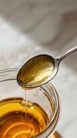 Honey being poured from a spoon into a jar photo