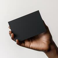 a dark skin hand holding a black blank business card The shot should be taken from a side perspective with the business card facing the camera photo