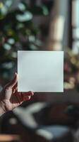 a hand holding a white blank rectangle paper, paper position horizontally, realistic photo