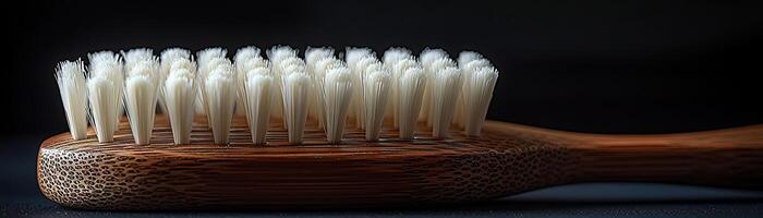 A handcrafted wooden brush with white bristles, contrasted against a dark, moody background, capturing a sense of timeless utility and elegance photo
