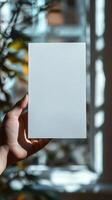 a hand holding a white blank rectangle paper, paper position horizontally, realistic photo