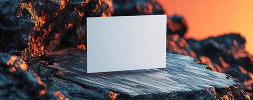 a composition of blank white business card hovering partially over a surface The surface is slab of dark rock and wood on a split color background The card is center and in focus o photo