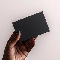 a dark skin hand holding a black blank business card The shot should be taken from a side perspective with the business card facing the camera photo