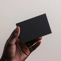 a dark skin hand holding a black blank business card The shot should be taken from a side perspective with the business card facing the camera photo