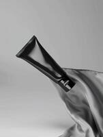 A black tube of face cream on a gray background. photo