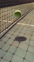 Tennis ball caught in net with shadow on the ground. photo