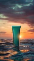 Teal tube of sunscreen floating in the ocean at sunset. photo