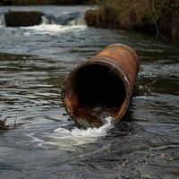 un oxidado tubo es dumping tóxico residuos dentro un río, cuales es causando el agua a volverse contaminado y inseguro para Bebiendo o nadar. foto