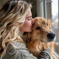 Woman with long blonde hair embraces her golden retriever, sharing a tender moment by the window. photo