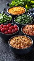 A rainbow of healthy ingredients including berries, lentils, and greens, artistically arranged in bowls on a dark, textured surface, symbolizing balanced and vibrant nutrition photo