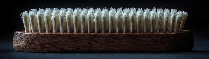 A handcrafted wooden brush with white bristles, contrasted against a dark, moody background, capturing a sense of timeless utility and elegance photo