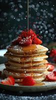A decadent stack of pancakes topped with fresh strawberries and drizzled in maple syrup. photo