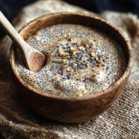 A bowl of creamy chia seed pudding with a wooden spoon, set on a rustic burlap cloth, highlighting the simplicity and healthiness of natural foods, rich and inviting photo