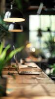 Modern coworking office space with a wooden desk, open laptop, greenery, and industrial light fixtures creating a cozy work environment. photo