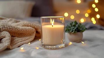 Blank clear straight candle glass surrounded by a stack of books, a small vase with flowers, and warm ambient lighting, modern warm bedroom mockup, chic and cozy photo