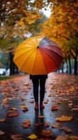 Top view of person under bright umbrella, with autumn fallen leaves on the sidewalk. Vertical banner photo