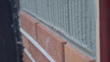 A bricklayer is seen applying mortar on a wall as part of the building construction process video