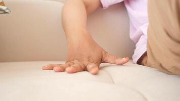 A closeup view of a hand gently resting on a cozy, beige couch in a peaceful home setting video