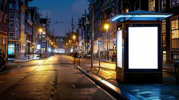 Blank advertising billboard at illuminated bus stop in empty urban street. Mockup for advertisement photo