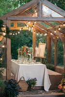 decorated greenhouse in trendy wedding setting with dinner table, candles and candle lights. photo
