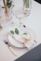 Table setting with napkin on empty white plate, wineglasses and cutlery on table, copy space. Place setting at wedding reception. Table served for banquet photo