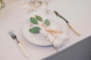 Table setting with napkin on empty white plate, wineglasses and cutlery on table, copy space. Place setting at wedding reception. Table served for banquet photo