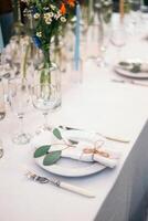 Table setting with napkin on empty white plate, wineglasses and cutlery on table, copy space. Place setting at wedding reception. Table served for banquet photo