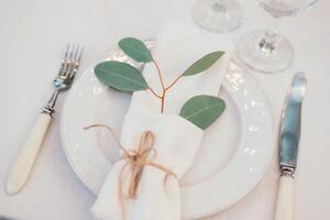Table setting with napkin on empty white plate, wineglasses and cutlery on table, copy space. Place setting at wedding reception. Table served for banquet photo