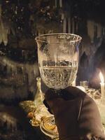 a person holding a glass of wine in front of candles photo