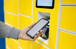 Close up of a man picks up mail from automated self-service post terminal machine photo