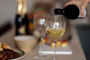 Close-up of an elegant glass with a long stem with champagne. The process of pouring sparkling wine into a goblet. photo