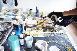 A woman uses a gas burner to draw in Fluid Art. Process of creating a painting with liquid acrylic paints. photo