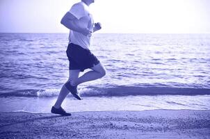 Man running on the beach at sunset photo