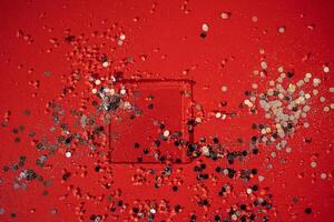 Transparent glass square mockup for smears of cosmetics. Bright red background with silver sparkles and confetti. photo