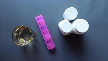 top view of medical pills box, container and glass of water on black background video