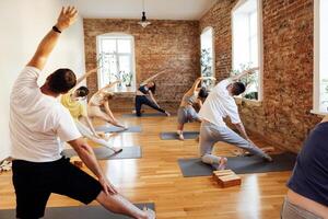 Group of athletic attractive people are practicing yoga class with instructor. photo