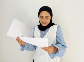 Asian Muslim businesswoman holding blank paper and looking at it isolated on white background photo
