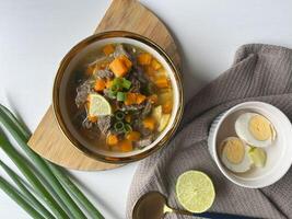 Beef soup is made from beef broth cooked with spices served with vegetables such as potatoes, carrots, spring onions, lime and boiled eggs. Perfect for articles, recipe books and creative production photo