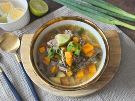 Beef soup is made from beef broth cooked with spices served with vegetables such as potatoes, carrots, spring onions, lime and boiled eggs. Perfect for articles, recipe books and creative production photo