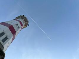 Lighthouse with clear blue sky in evening with flight path photo