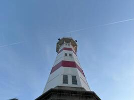 Lighthouse with clear blue sky in evening with flight path photo