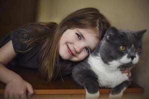 Cute little girl with cat hugging at home. First pet photo