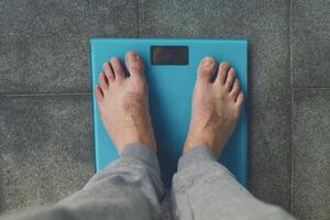 Man standing on weight scale photo