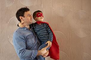 Joyful daddy carries small child who embraces him and smiles happily photo