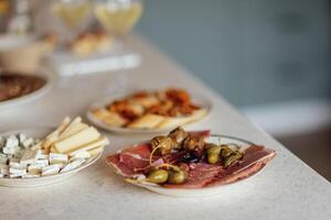 Two glasses of cool champagne and plates with various snacks on a table photo